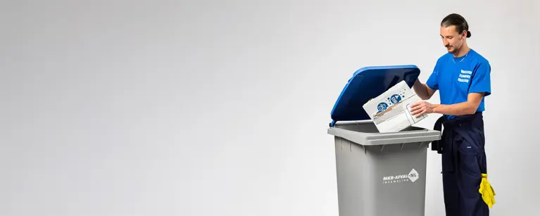Papiercontainer met ondernemer die karton in de 240 liter rolcontainer van MKB-afval gooit.